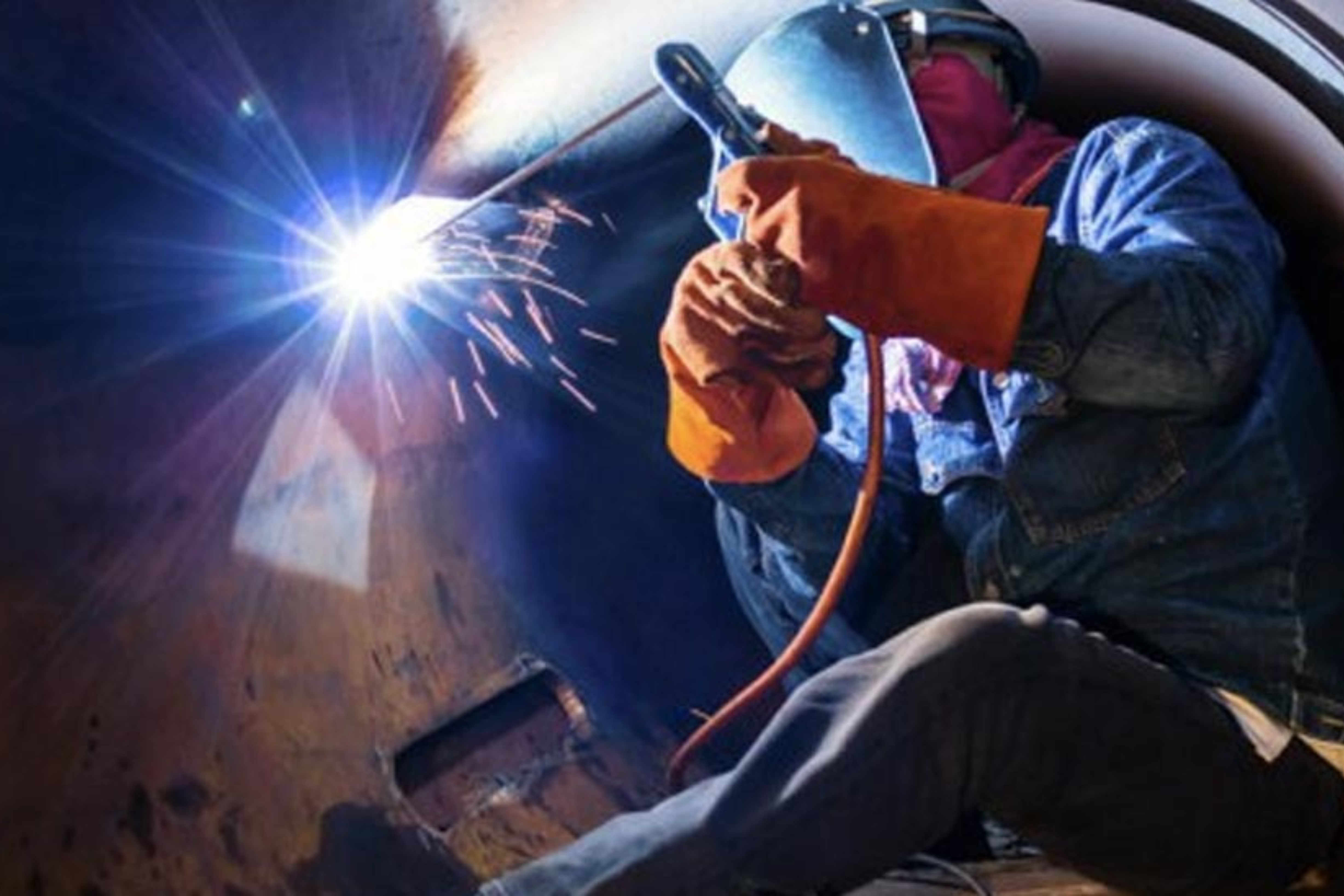 Imagen de una persona, con EPIs, dentro de un espacio confinado realizando tareas de soldadura.