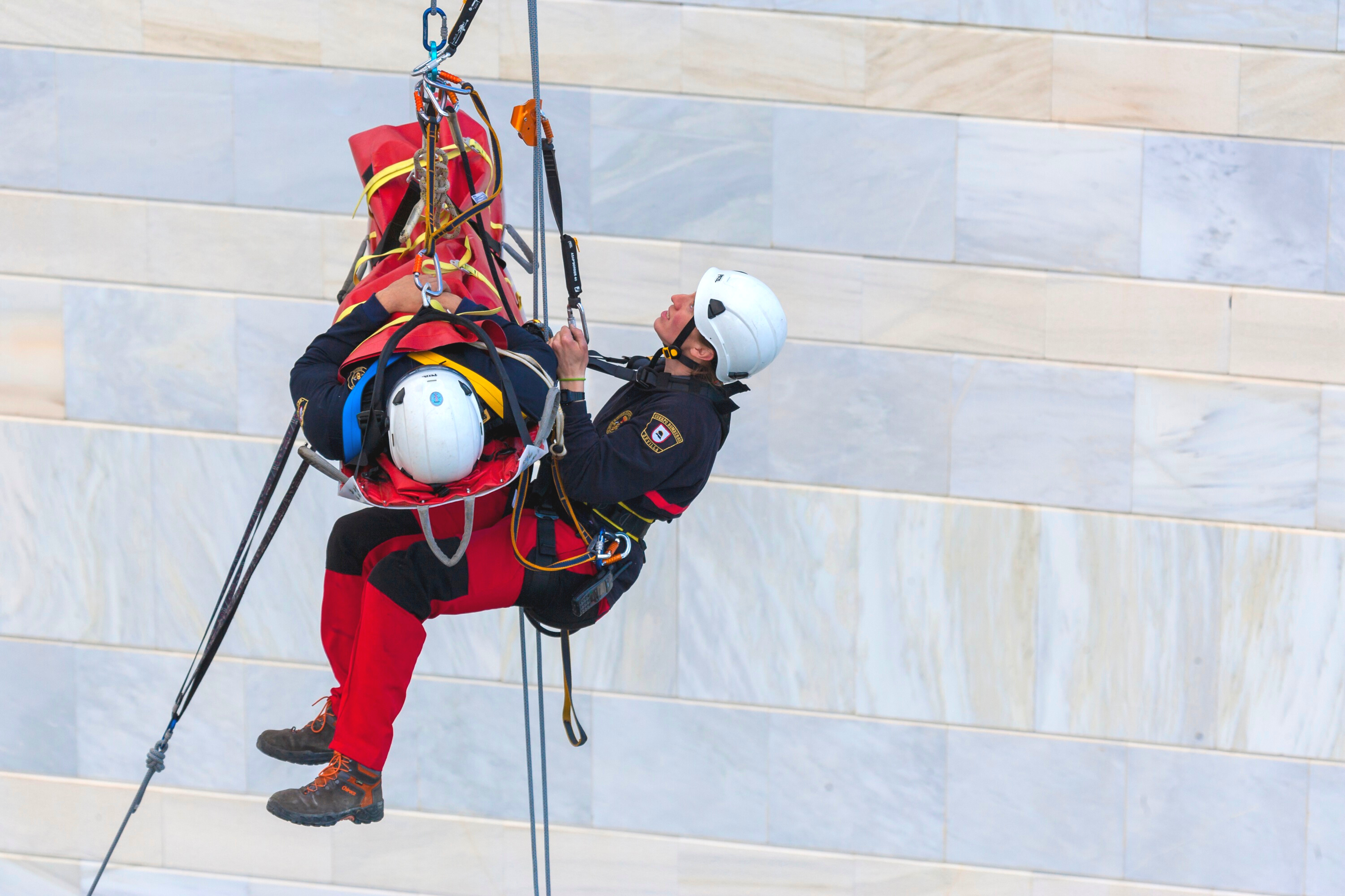 Una persona rescatando a otra, en camilla, mediante técnicas de acceso por cuerda.