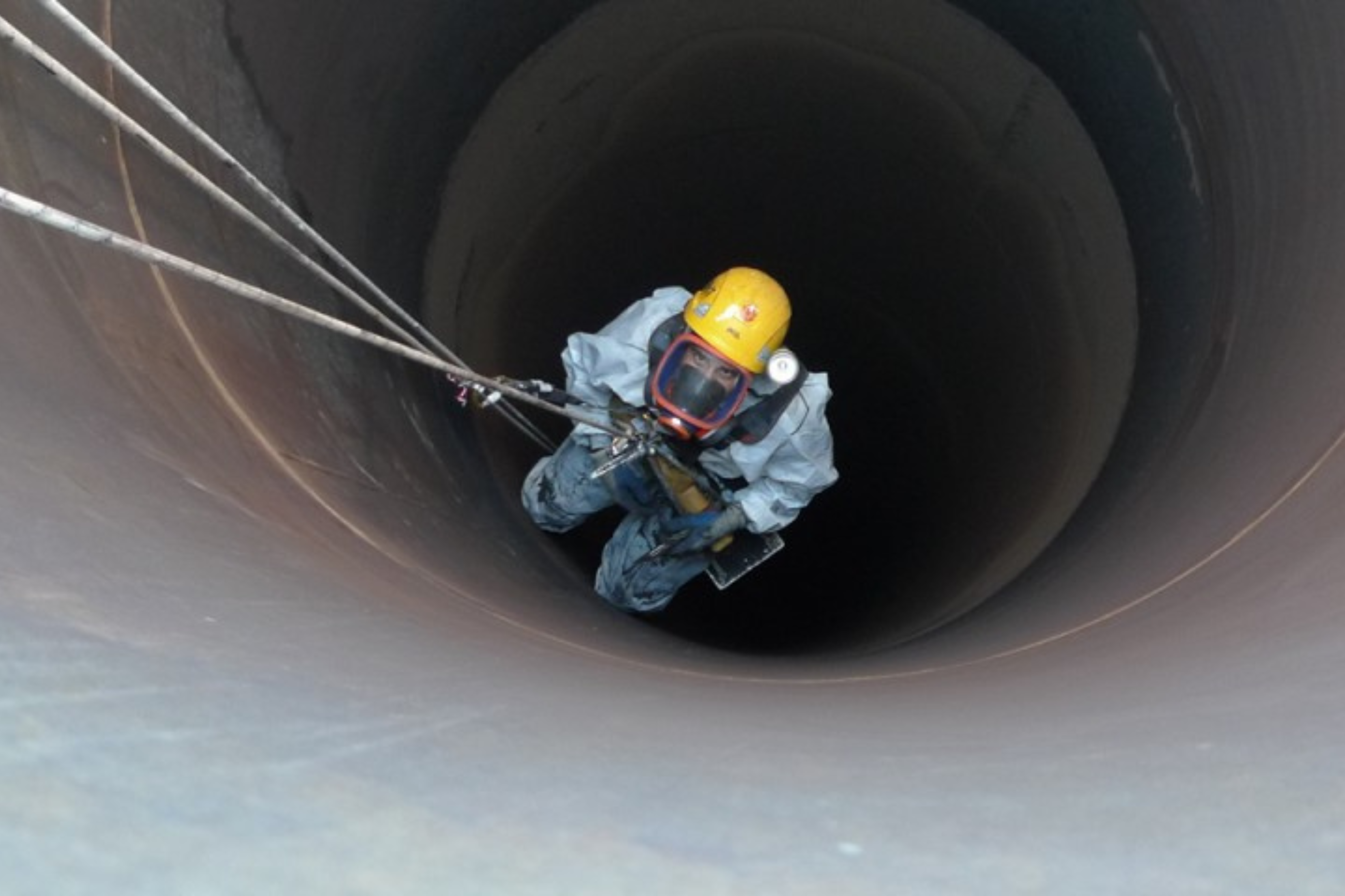Un hombre con traje de seguridad se mete en un espacio confinado.