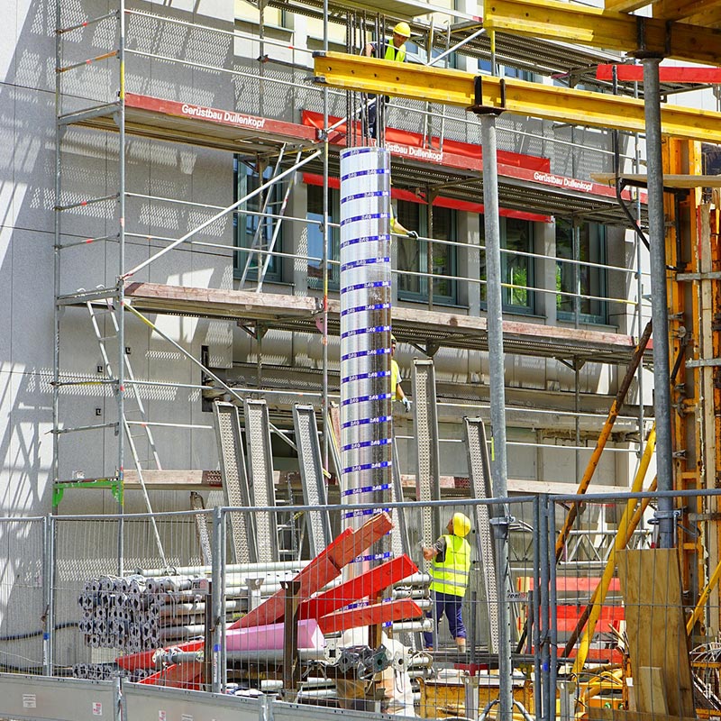 Imagen de una obra de construcción con un andamio y trabajadores sobre el.
