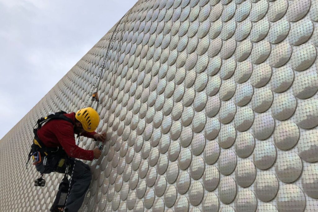Un trabajador realizando trabajos verticales, con todos sus epis, incluido bloqueador para trabajos en altura.