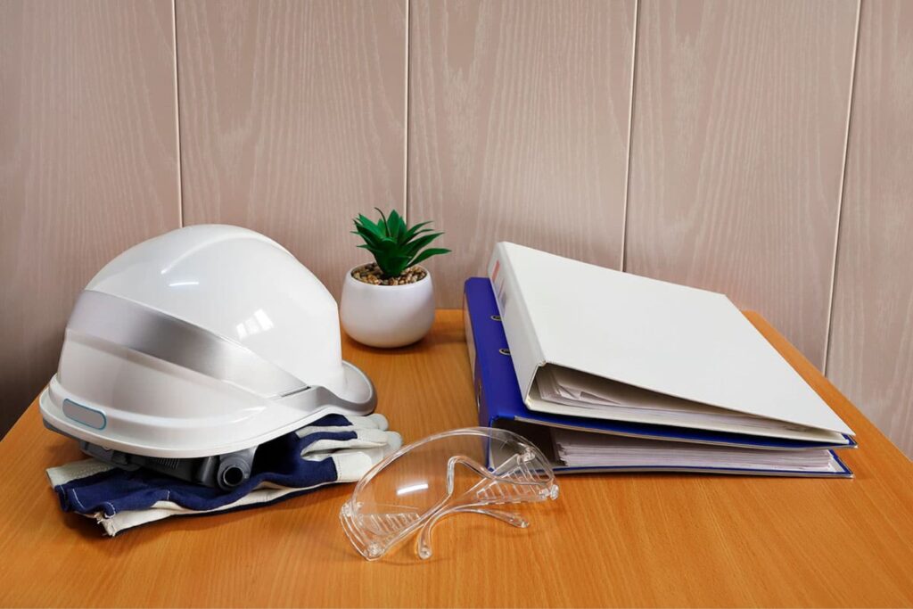 Imagen de unos documentos y varios EPIs para simbolizar las consecuencias del incumplimiento de la normativa de PRL.